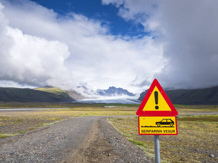 Schild an einem leeren Feldweg gegen den bewölkten Himmel am Svinafellsjokull, Island - LAF02512