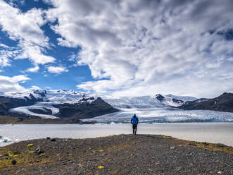 Man looking at view from mountain against cloudy sky at Breidamerkurjokull, Iceland - LAF02524