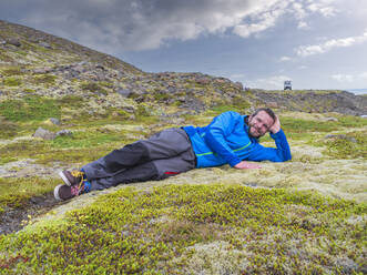 Mid adult man relaxing on land by ring road, Iceland - LAF02527