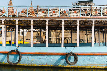 India, Uttar Pradesh, Varanasi, Old tourboat moored in front of city buildings - JMPF00603