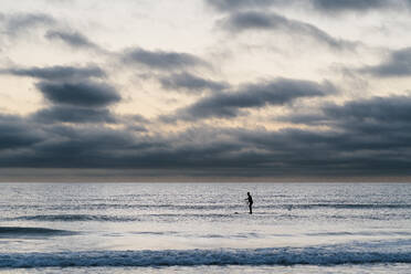 Female paddleboarder surfing on sea during dawn - EGAF01028