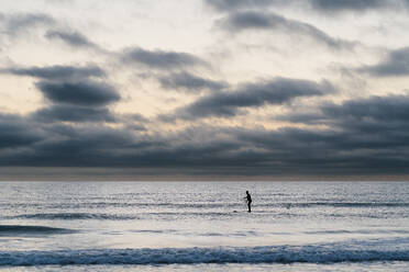 Weibliche Paddleboarderin surft in der Morgendämmerung auf dem Meer - EGAF01028