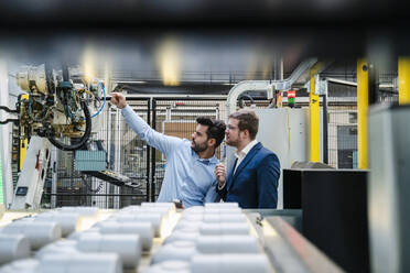 Male colleagues analyzing machinery in industrial factory - DIGF13117