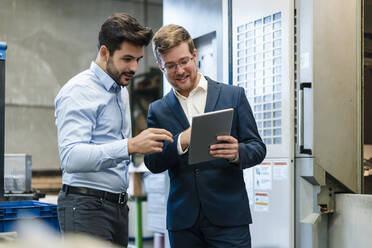 Smiling businessmen using digital tablet at industry - DIGF13183