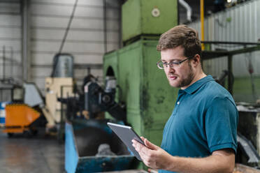 Male factory worker using digital tablet while standing in manufacturing industry - DIGF13229