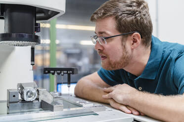 Männlicher Fabrikarbeiter bei der Analyse einer Vermessungsmaschine in einer Fabrik - DIGF13238