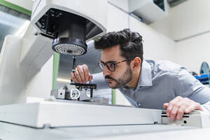 Männlicher Unternehmer bei der Prüfung einer Vermessungsmaschine in einer Fabrik - DIGF13241