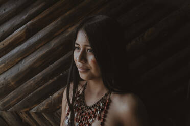 Nachdenkliche junge Guarani-Frau, die nachdenklich gegen eine Bambuswand schaut, Misahualli, Ecuador - DSIF00206