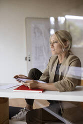 Geschäftsfrau schaut weg, während sie zu Hause ein digitales Tablet benutzt - PESF02168