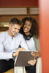 Smiling couple using digital tablet while sitting at home - PESF02215