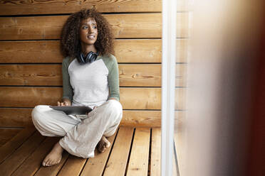 Woman with digital tablet sitting with cross-legged at home - PESF02218