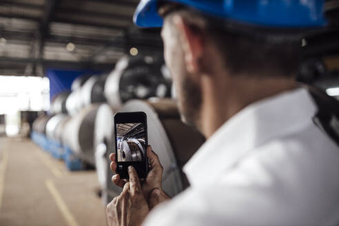 Geschäftsmann, der ein Foto mit seinem Smartphone in der Industrie macht - GUSF04712