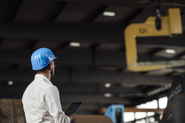 Männlicher Unternehmer hält digitales Tablet in einer Fabrik - GUSF04819