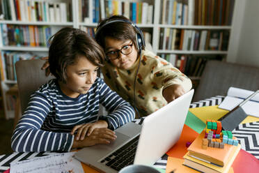 Boys looking at laptop while e-learning in living room - VABF04028