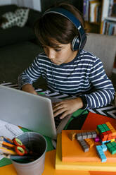 Pre-adolescent boy using laptop during homeschooling - VABF04036