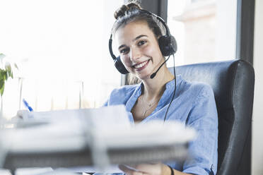 Young businesswoman smiling while sitting at office - UUF22084