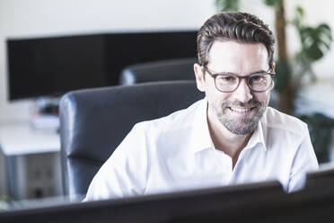 Smiling businessman working at office - UUF22090