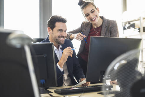 Geschäftsleute, die einen Computer benutzen, während sie im Büro zusammenarbeiten - UUF22125