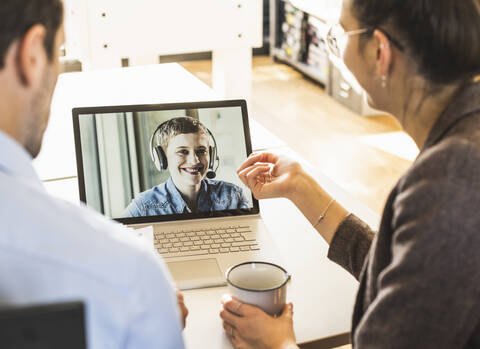 Team having meeting over video conference on laptop at office stock photo