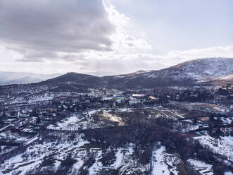 Spain, Community of Madrid, Navacerrada, Aerial view of village in snow-covered Sierra de Guadarrama range - RSGF00443