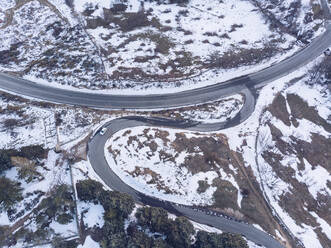 Aerial view of lone car driving along empty highway in Sierra de Guadarrama range - RSGF00445
