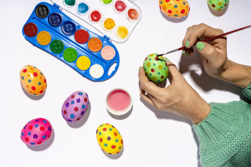 Hands of woman painting Easter eggs with colorful watercolors - GEMF04403