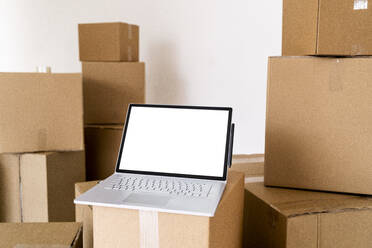 Laptop on cardboard box in living room of new house - GIOF09687