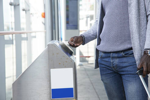 Geschäftsmann scannt Fahrkarte an der Schranke des Bahnhofs - PMF01556