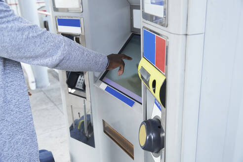 Hand eines männlichen Pendlers, der einen Fahrkartenautomaten am Bahnhof benutzt - PMF01568