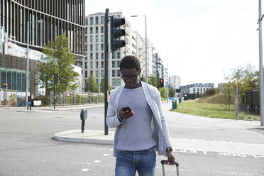 Male entrepreneur using mobile phone while walking on street in city - PMF01572