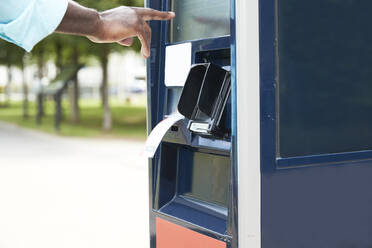 Hand of male commuter using ticket machine on sunny day - PMF01607