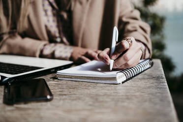 Geschäftsfrau schreibt am Schreibtisch im Büro in ein Tagebuch - EBBF01560