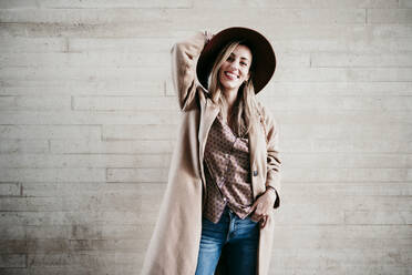 Stylish smiling beautiful woman posing against wall - EBBF01575