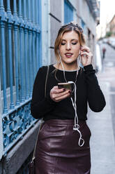 Stylish woman using mobile phone while standing on street - JMPF00624