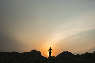 Silhouette einer Person, die die untergehende Sonne bewundert - JMPF00636