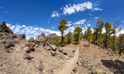 Man sitting on rock while hiking in Teide National Park, Tenerife, Canary Islands, Spain - WWF05703