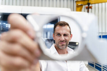 Businessman examining shape of equipment in industry - DIGF13290