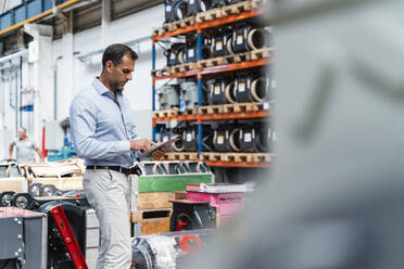 Male entrepreneur concentrating while using digital tablet standing at industry - DIGF13330