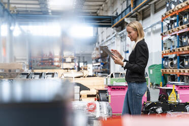 Female entrepreneur using digital tablet while standing in industry - DIGF13334