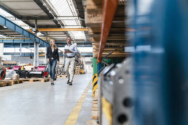 Geschäftsmann und weibliche Kollegen mit digitalem Tablet beim Spaziergang in der Industrie - DIGF13338