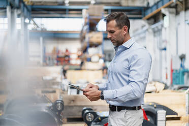 Businessman using digital tablet while standing in industry - DIGF13363