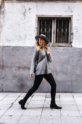 Attraktive modische Frau mit Hut, die beim Gehen auf der Straße wegschaut - JMPF00644