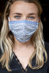 Porträt einer jungen blonden Frau mit blauer Gesichtsmaske. - MINF15273