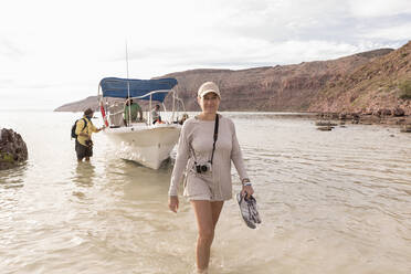 Woman walking to shore from power boat, Sea of Cortes - MINF15290