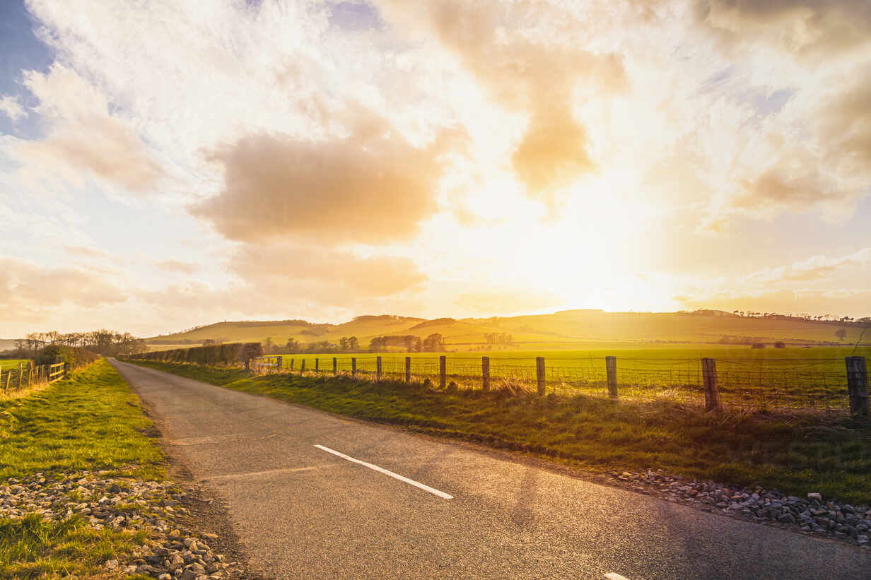 Empty country road in rural landscape at sunset stock photo