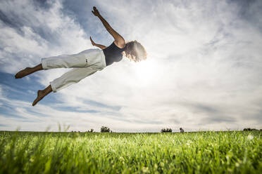 Junge weibliche Athletin macht akrobatische Aktivität im Park gegen bewölkten Himmel - ABAYF00029