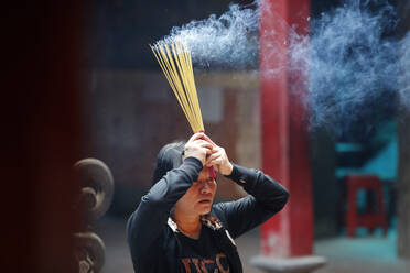 Taoist temple, Emperor Jade pagoda (Chua Phuoc Hai), Taoist worshipper burning incense sticks, Ho Chi Minh City, Vietnam, Indochina, Southeast Asia, Asia - RHPLF18253