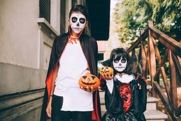 Bruder und Schwester in Halloween-Kostümen mit Jack-O-Lanterns - CUF56575