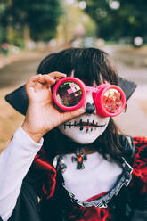 Mädchen trägt Halloween-Kostüm mit Gesichtsbemalung und Schutzbrille - CUF56576