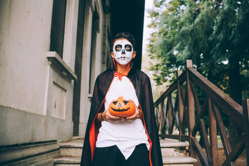 Junge im Halloween-Kostüm, der eine Jack-O-Lantern hält - CUF56577